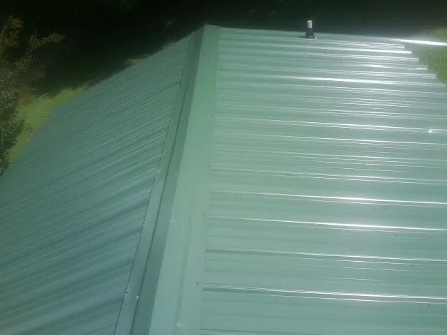New green metal panels meeting at the ridge of a roof — Flat Roof Repair work by our crew in Greenbackville