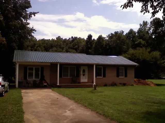 Dark green metal roof on a brick ranch with a covered porch in Greenbackville