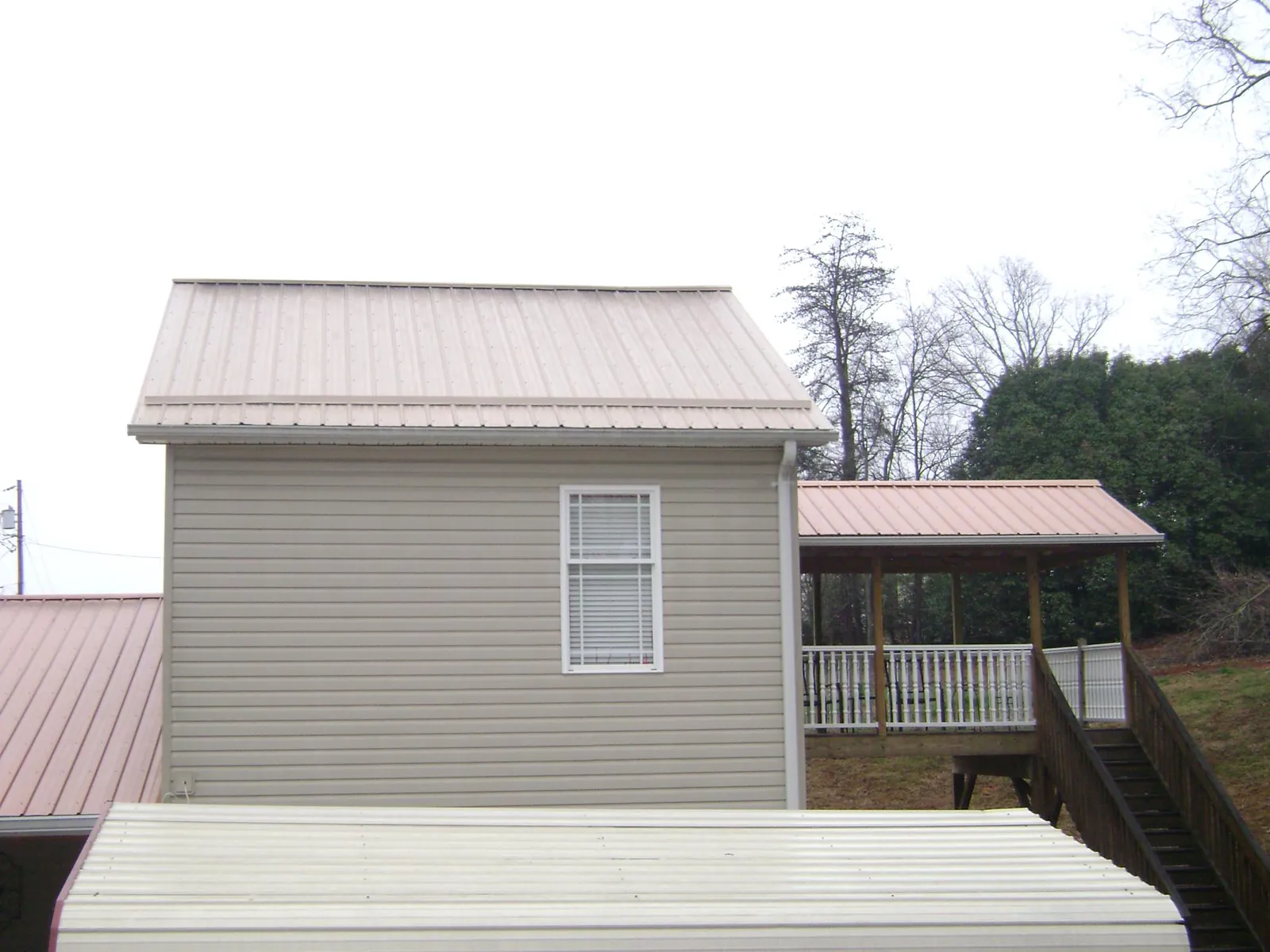 Tan metal roofs on a two story addition and attached porch, from a Roof Replacement job in Greenbackville